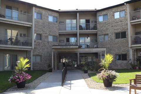 A courtyard of apartment buildings with potted plants and a bench.