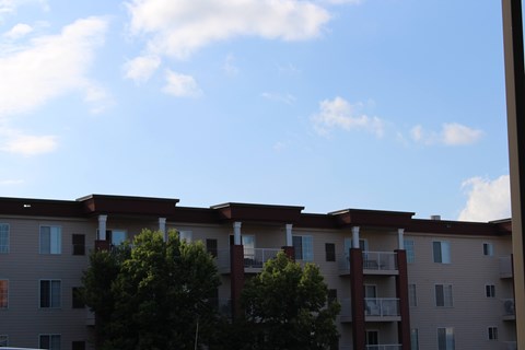Apartment building with balconies and trees in front.