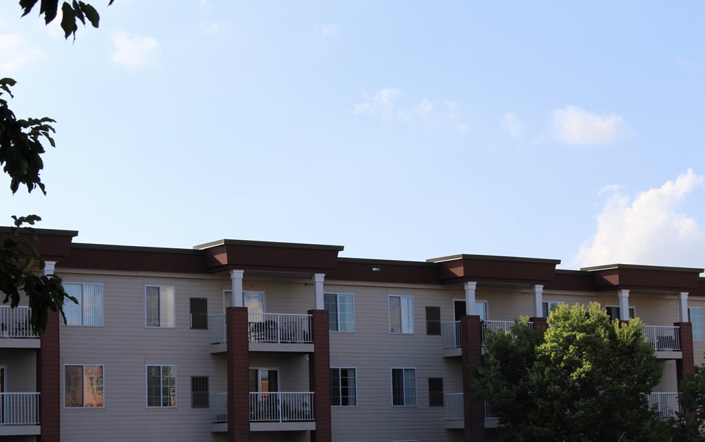 Apartment building with balconies and trees in front.