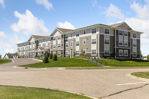 A large, multi-story apartment building with a parking lot in front.