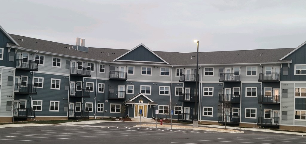 a large apartment building on the corner of a parking lot