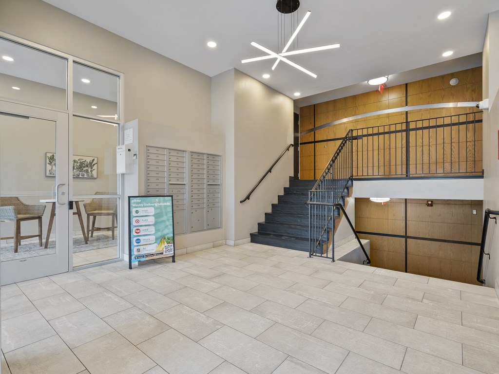 Lobby with stairs going to the hallways with mail area and seating area in the background