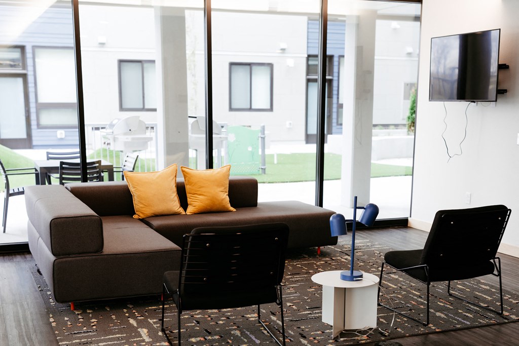 Lounge area including secitonal couch, chair, and TV next to windows looking into the courtyard