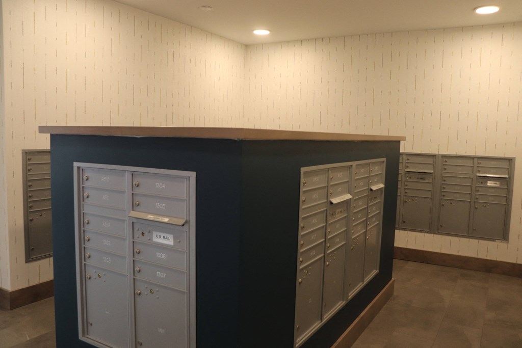 a view of the mail room in a building with mailboxes and filing cabinets
