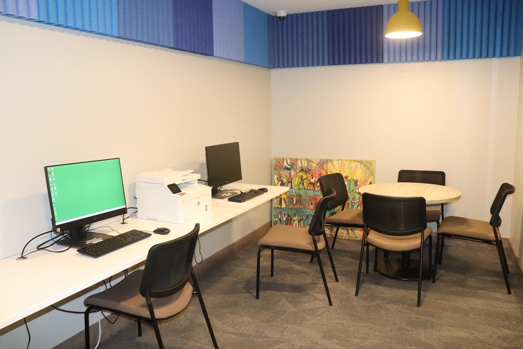 a computer room with desks and chairs and a computer monitor on a table