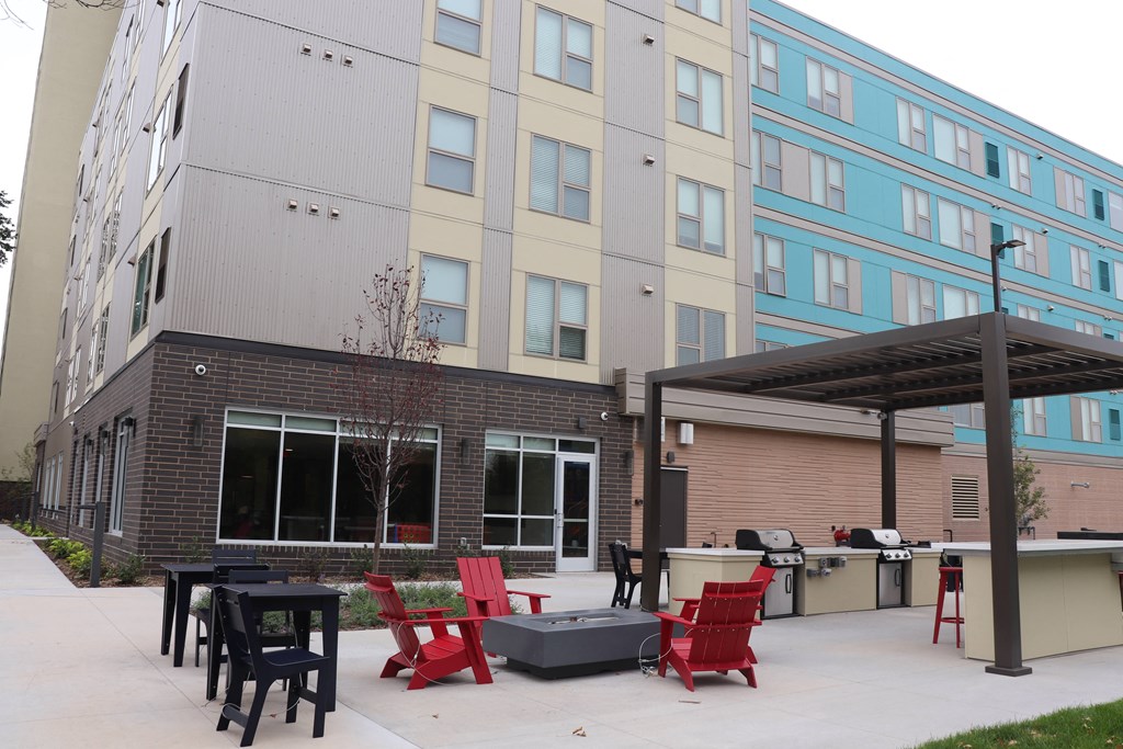 a patio with red chairs and tables in front of a building