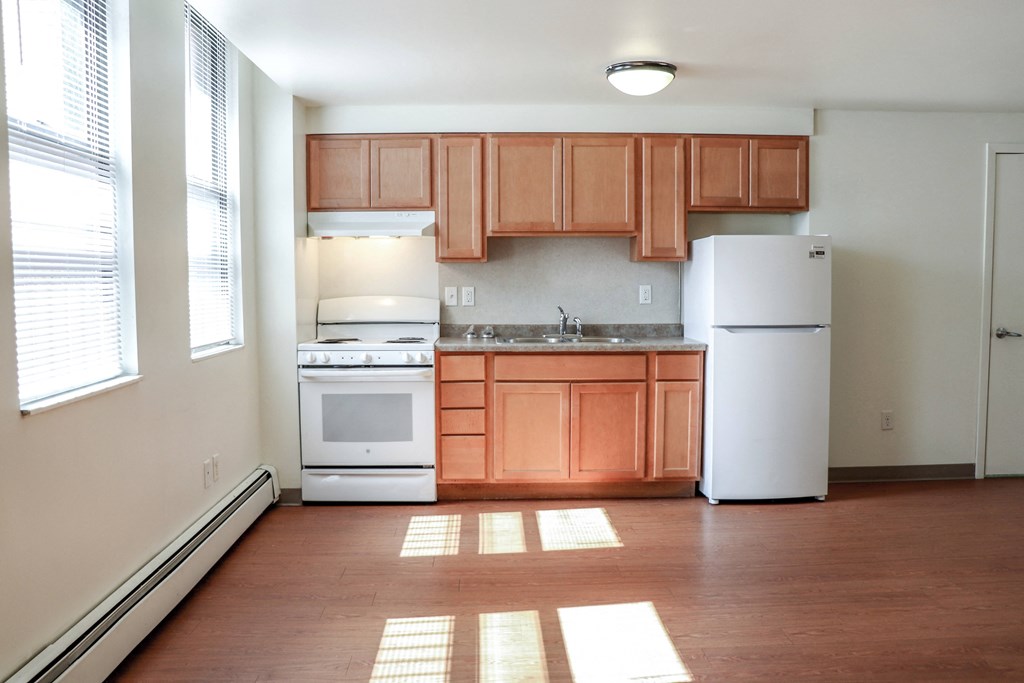 an empty kitchen with white appliances and wooden cabinets