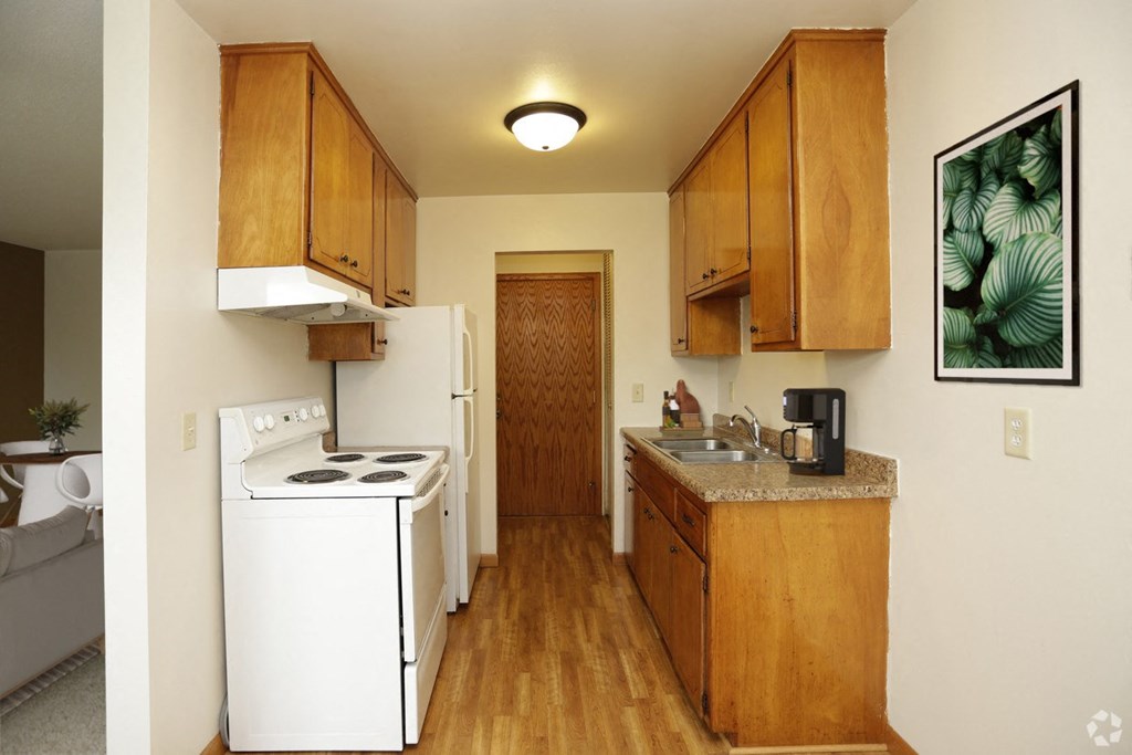 A kitchen with white appliances and wooden cabinets.