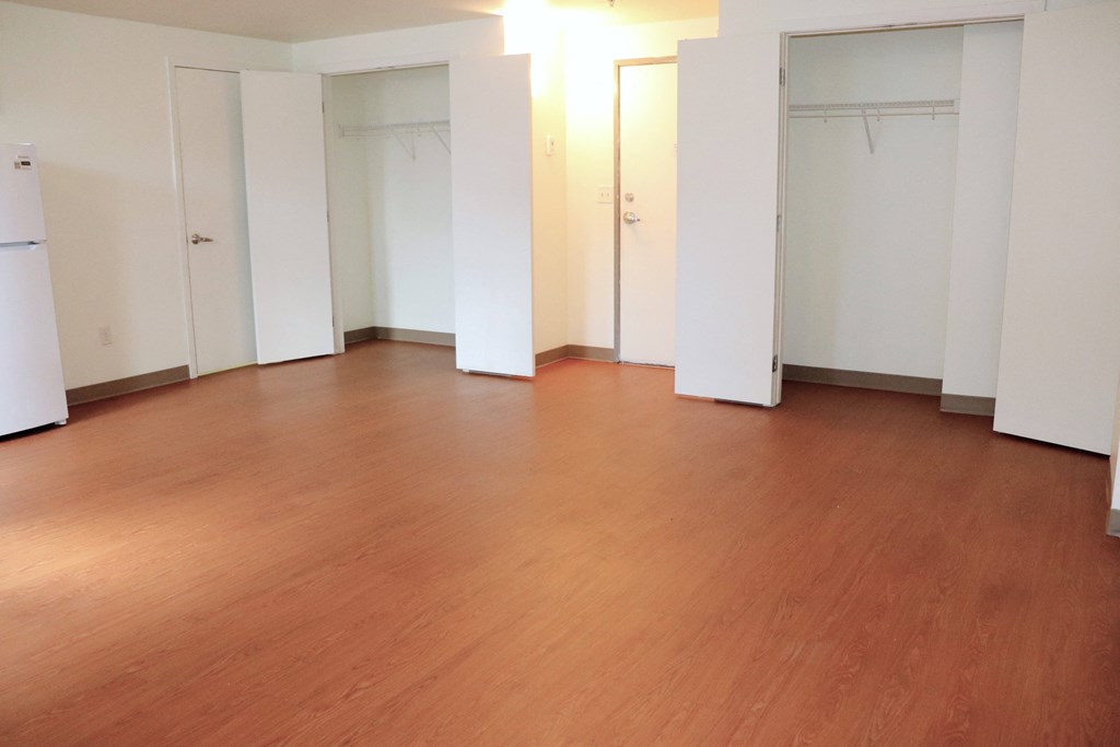 an empty living room with wood floors and white walls