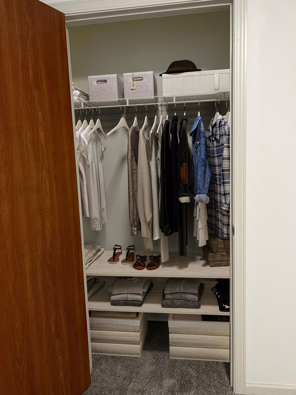 a walk in closet with white shelves and a wooden door