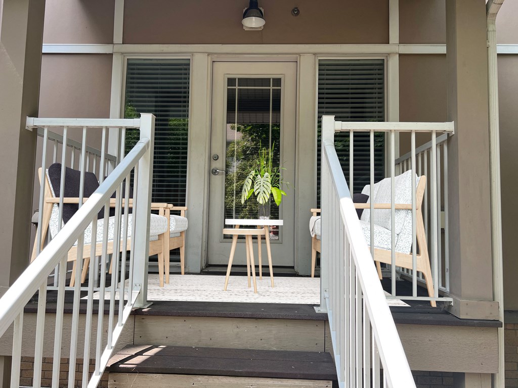 a porch with two chairs and a stool