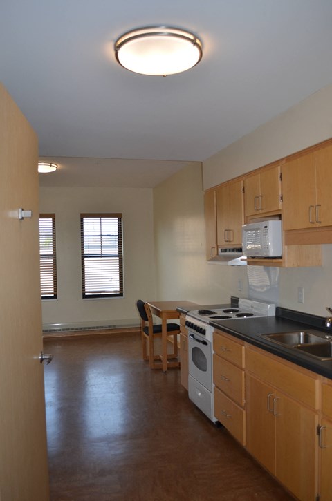 an empty kitchen with wooden cabinets and appliances and a dining room table