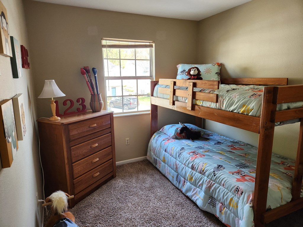 a bedroom with a bunk bed and a dresser and a window