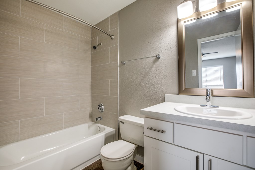 A bathroom with a white tub, toilet, and sink.