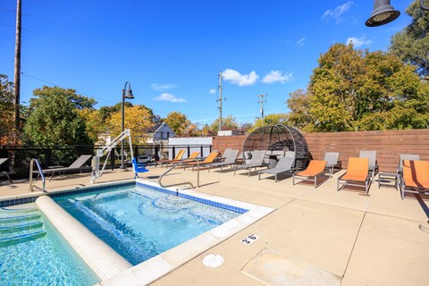 A swimming pool surrounded by chairs and trees.