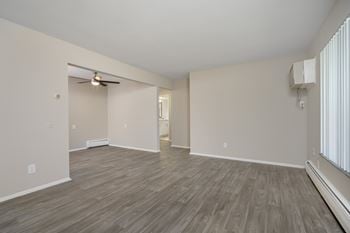 an empty living room with a ceiling fan and a window