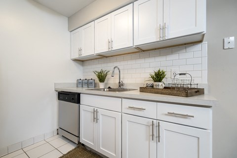 a white kitchen with white cabinets and a sink