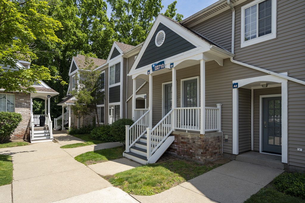 a sidewalk in front of two houses with stairs and a porch