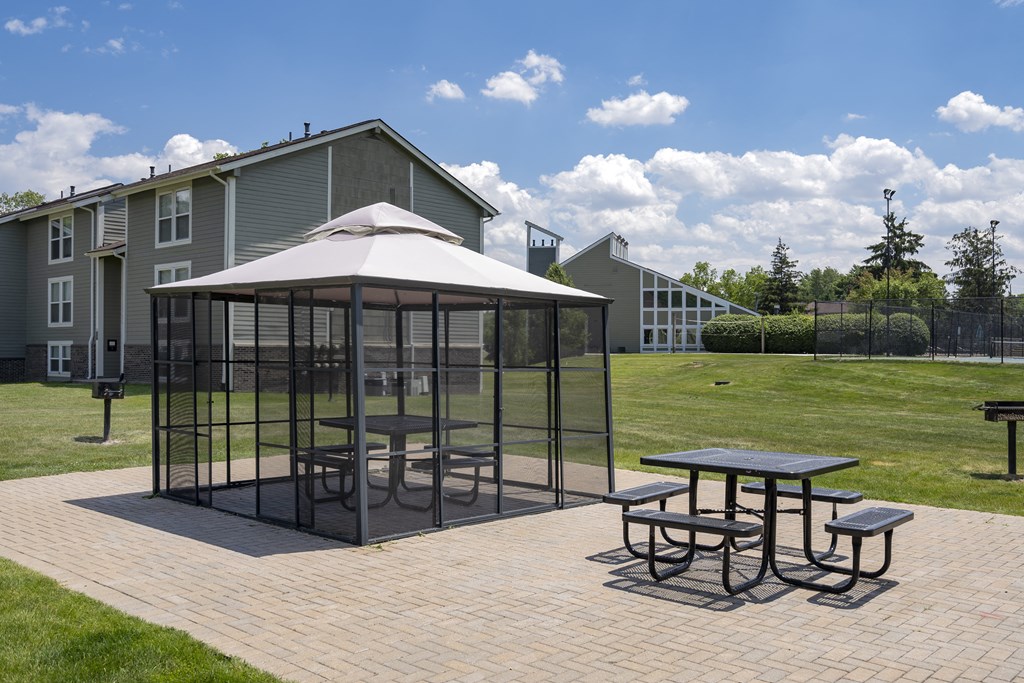 a gazebo with tables and chairs on a brick patio