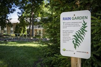 a sign for rain garden in front of a house