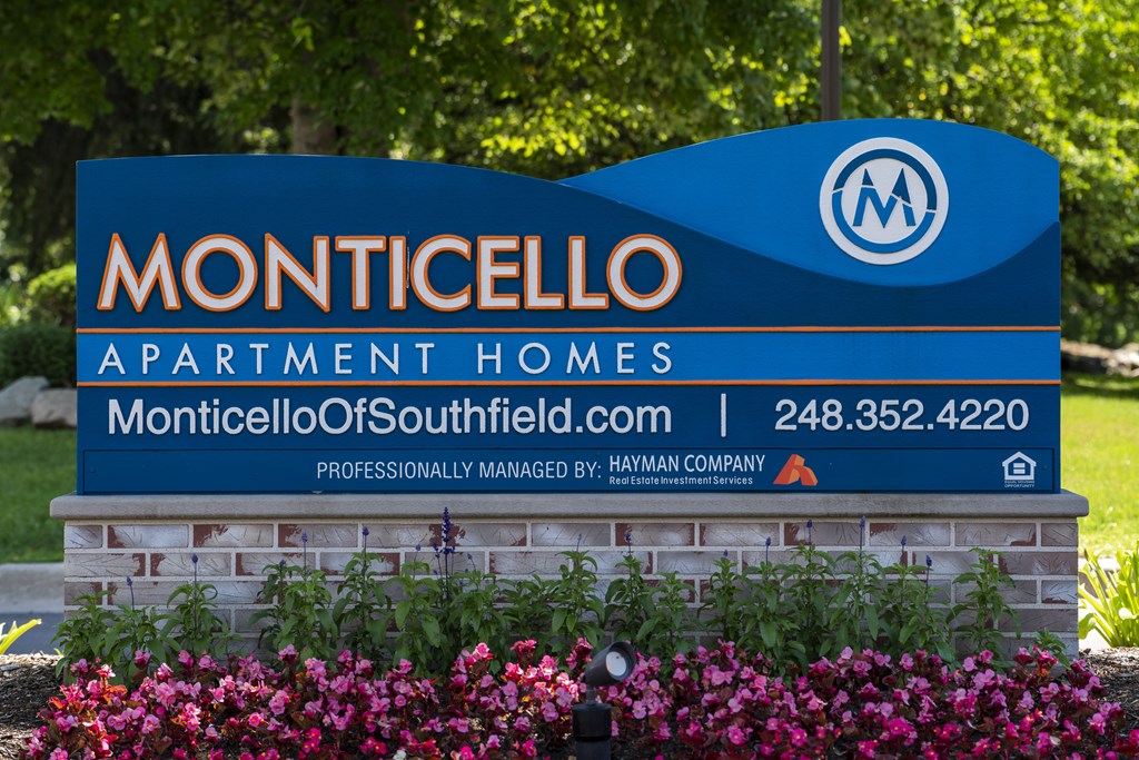 a sign for monticello apartment homes in front of flowers