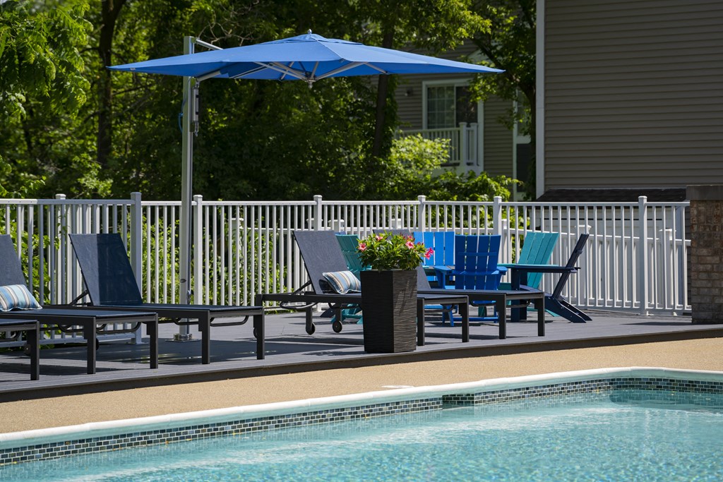 a swimming pool with blue chairs and a blue umbrella