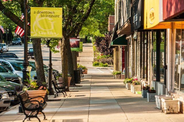 a sidewalk with benches and shops on a city street