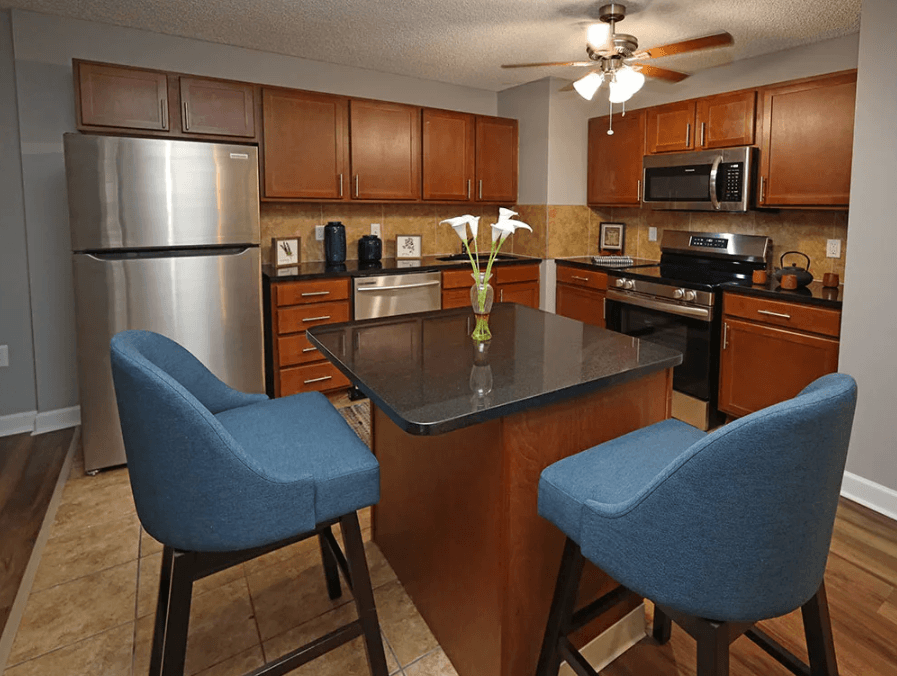 A kitchen with a black counter top and blue chairs.
