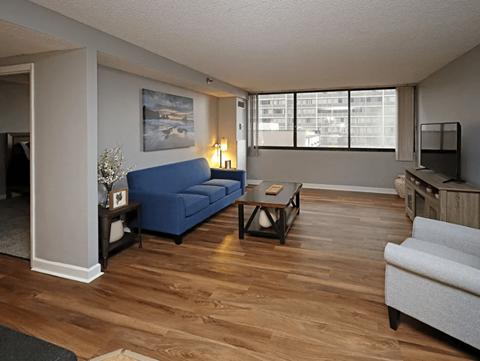 A living room with a blue couch and wooden floors.