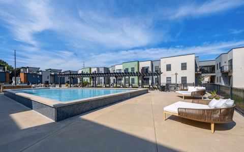 A pool area with a sun lounger and a building in the background.