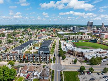 A cityscape with a mix of residential and commercial buildings, a large open field, and a clear sky.
