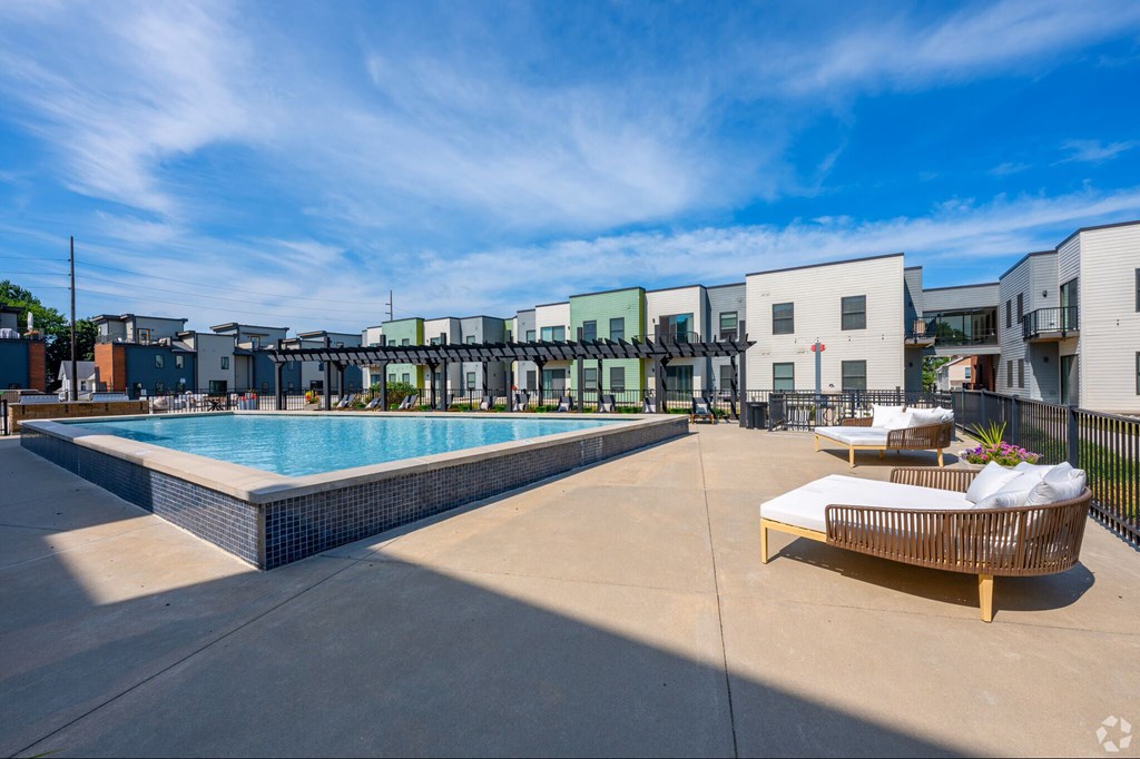A pool area with a sun lounger and a building in the background.