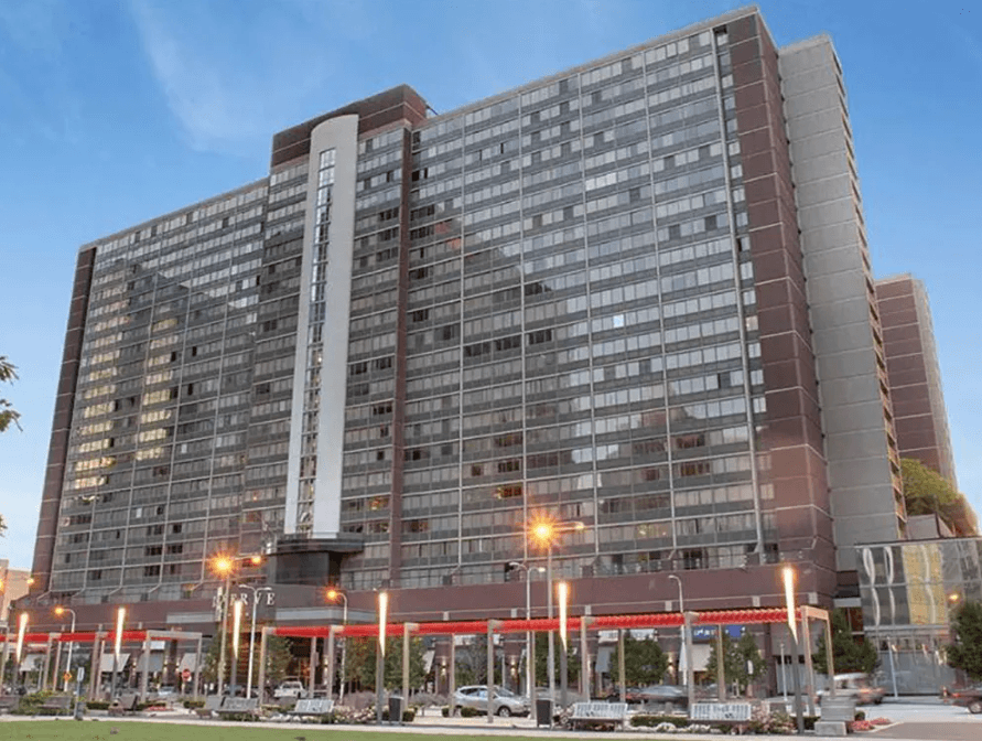A large red and grey building with a parking lot in front.