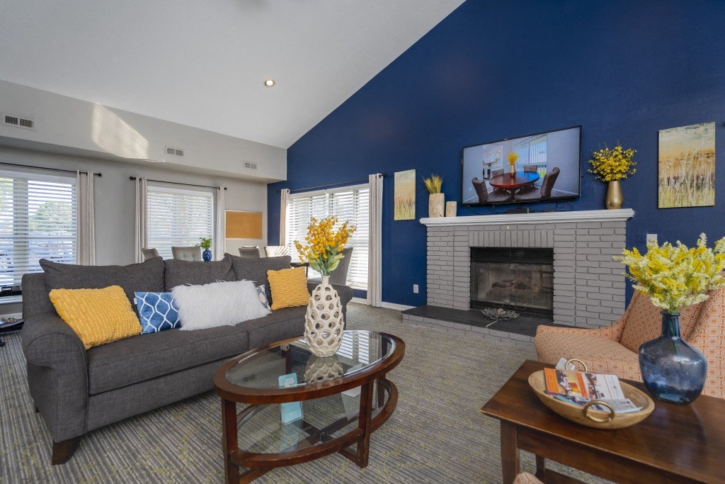 A living room with a grey couch, a glass coffee table, and a fireplace.