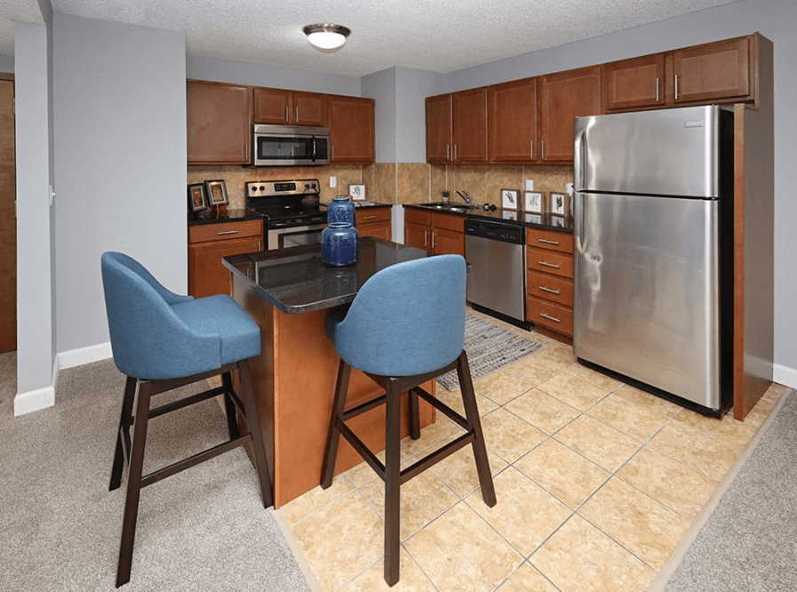 A kitchen with a table and two chairs.