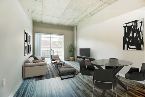 A living room with a grey table and black chairs.