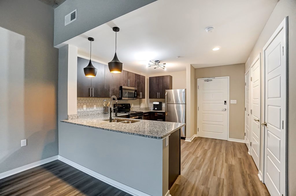A kitchen with a granite countertop and a stainless steel refrigerator.