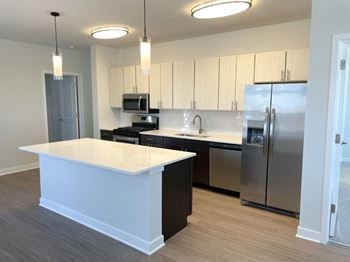a kitchen with an island and a stainless steel refrigerator