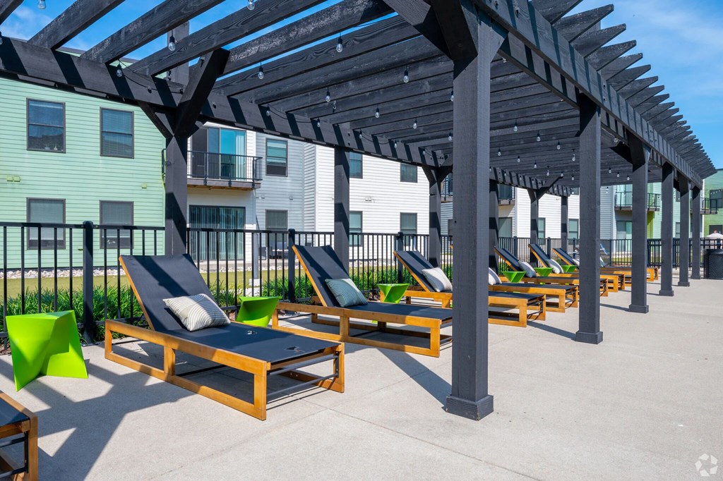 A sunny day at the outdoor lounge area with wooden sunbeds and a pergola.