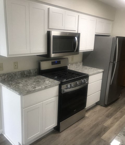a kitchen with white cabinets and a stove and a microwave