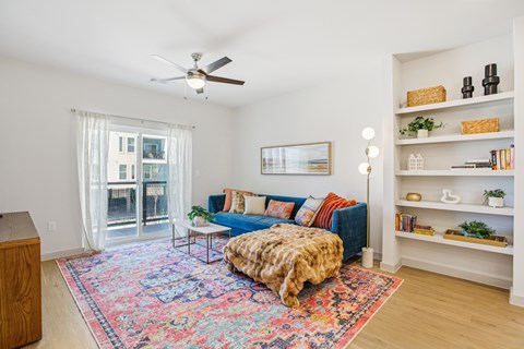 A living room with a blue couch and a colorful rug.