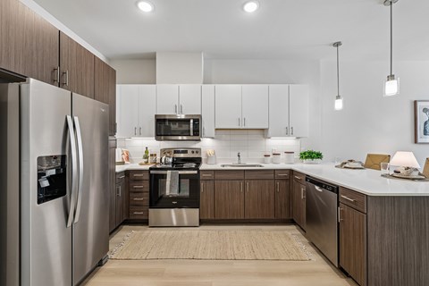 A modern kitchen with a refrigerator on the left and a sink in the middle.
