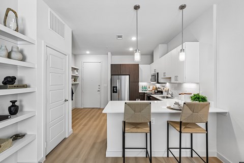 A kitchen with a white island and two chairs.