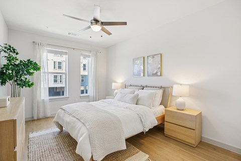 A bedroom with a large bed and a ceiling fan. at ThreeTwenty at the Vybe Apartments, Kyle, Texas