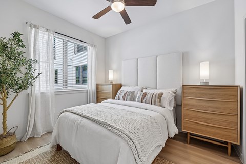 A bedroom with a white bed and a wooden dresser.