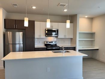 A modern kitchen with a white countertop and stainless steel appliances.