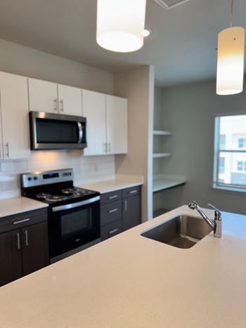A kitchen with a stove, microwave, and sink.