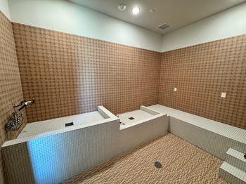 A bathroom with brown tiled walls and a white bathtub.