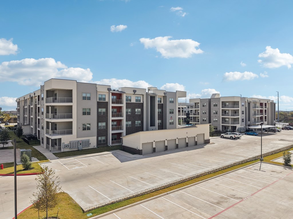A large apartment complex with a parking lot in front.