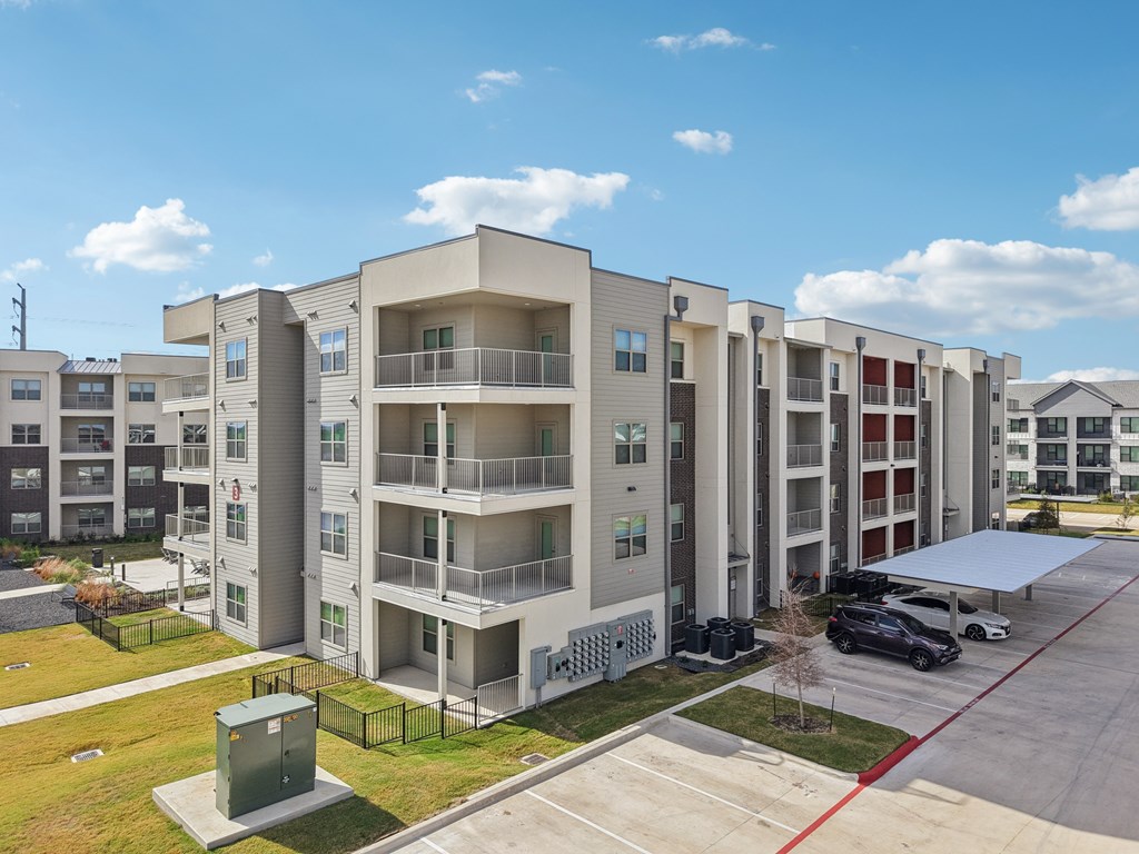 Apartment complex with a parking lot in front.
